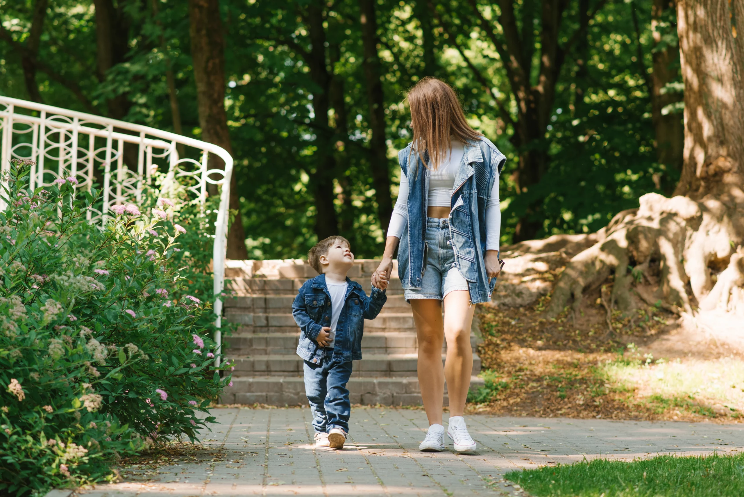 Stepmother and child walking hand in hand through a sunny Florida park, symbolizing love and connection in step-parent adoption.
