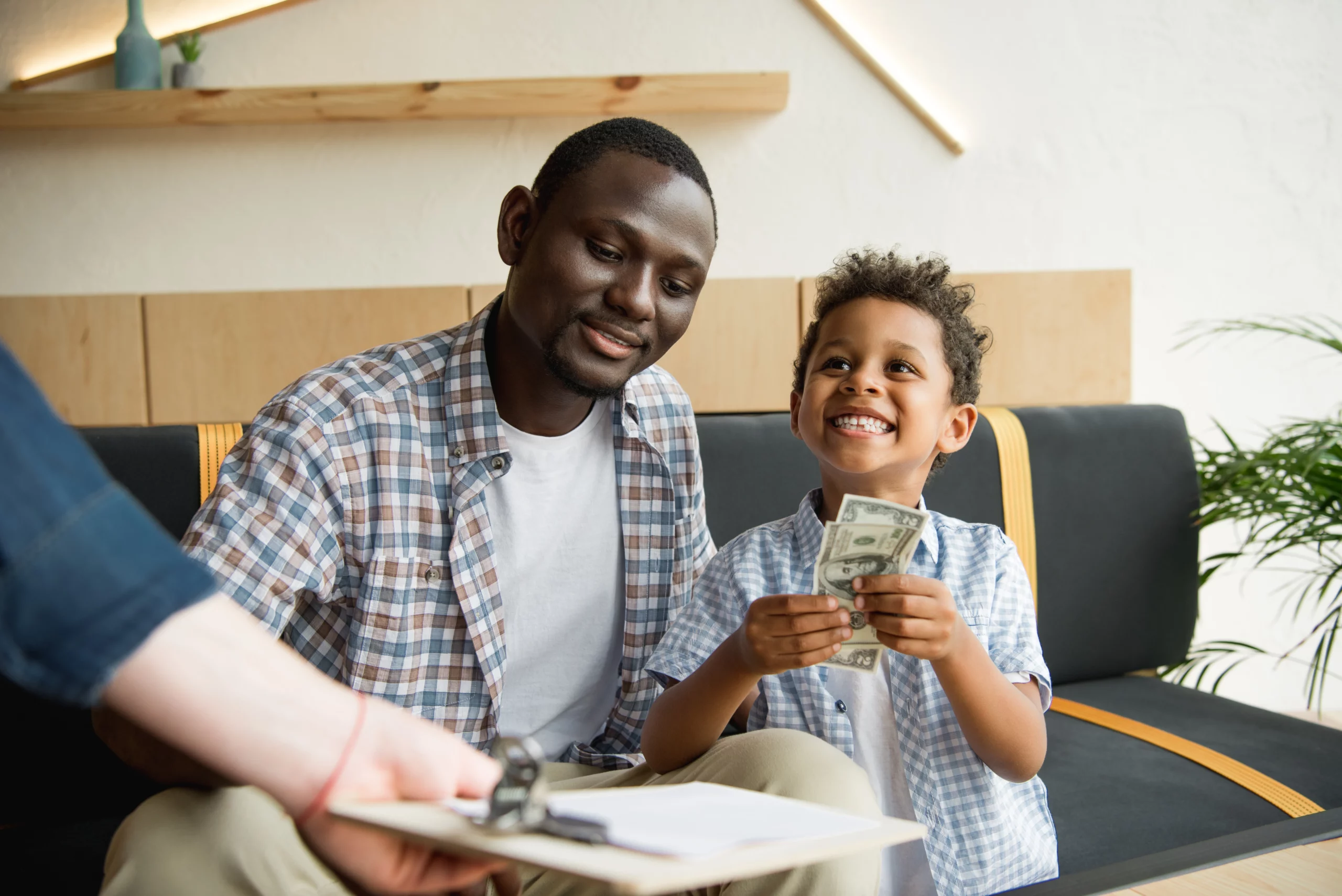 Father and son smiling as child holds cash, symbolizing child support.